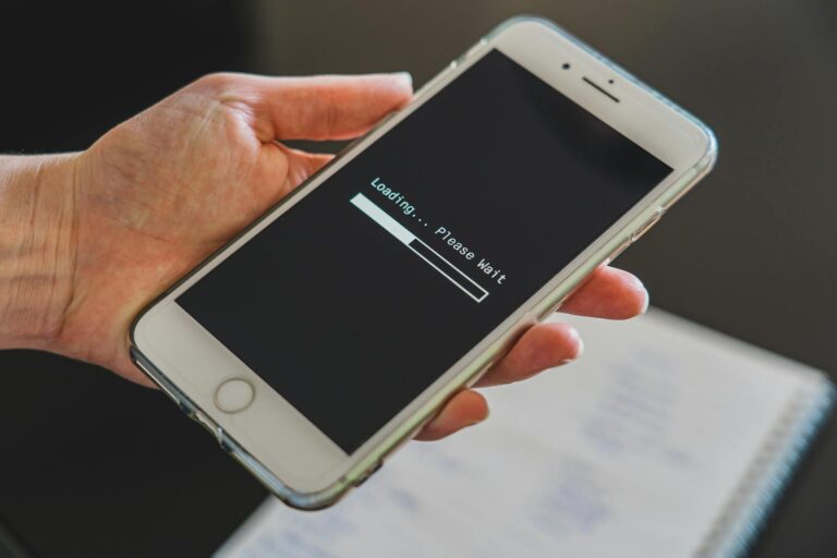 Close-up of a hand holding a smartphone with a loading screen displayed, showcasing technology usage.