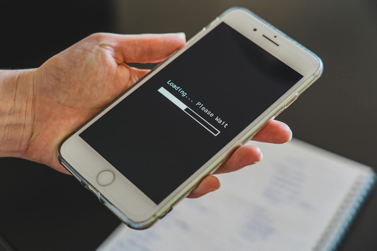 Close-up of a hand holding a smartphone with a loading screen displayed, showcasing technology usage.