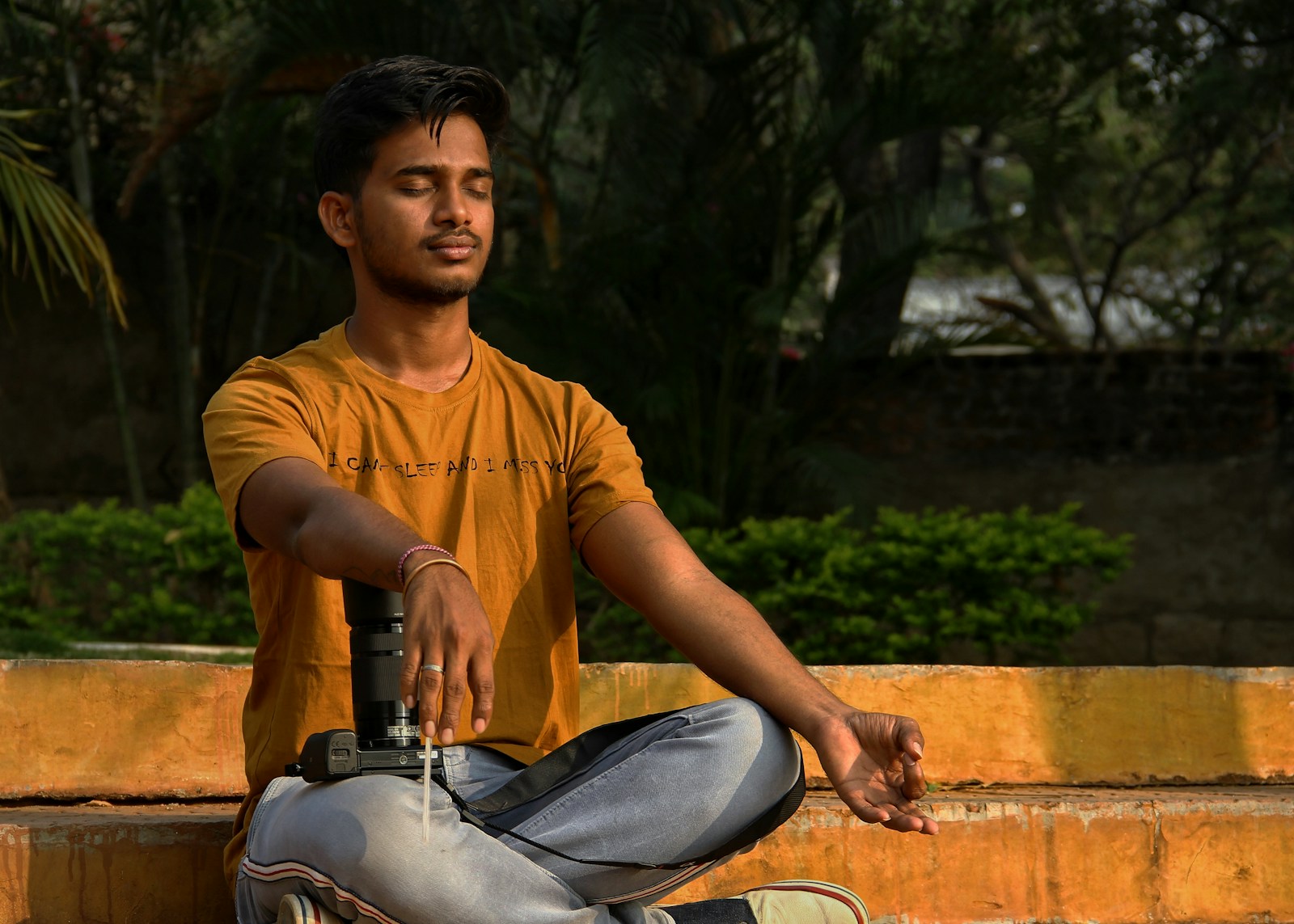 woman in orange crew neck t-shirt and black pants sitting on brown concrete bench during